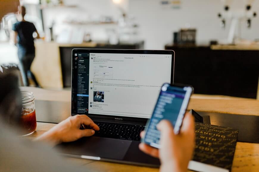 A person simultaneously looking at phone and computer
